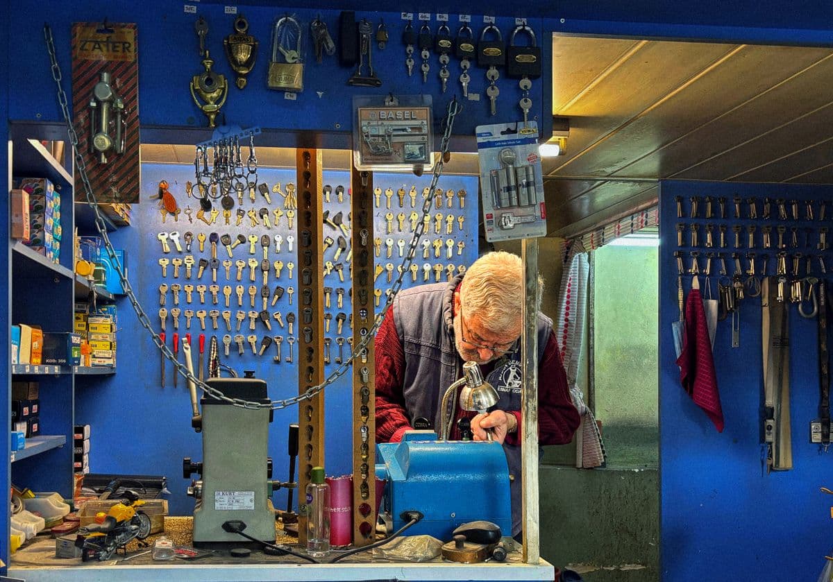 Artisan serrurier dans son atelier devant un mur de clés